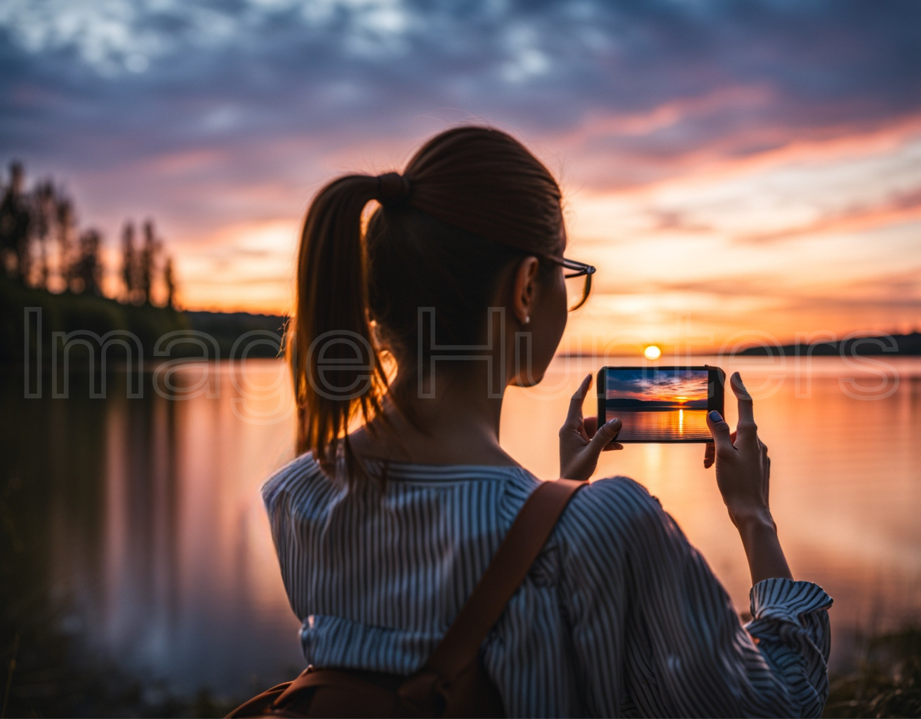 Woman capturing sunset with mobile phone